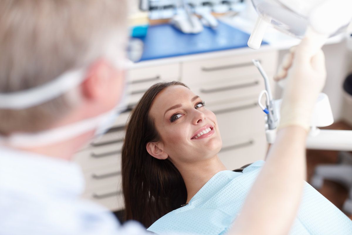 Clinic, happy and dentist with woman for consulting, teeth whitening and oral health on chair.