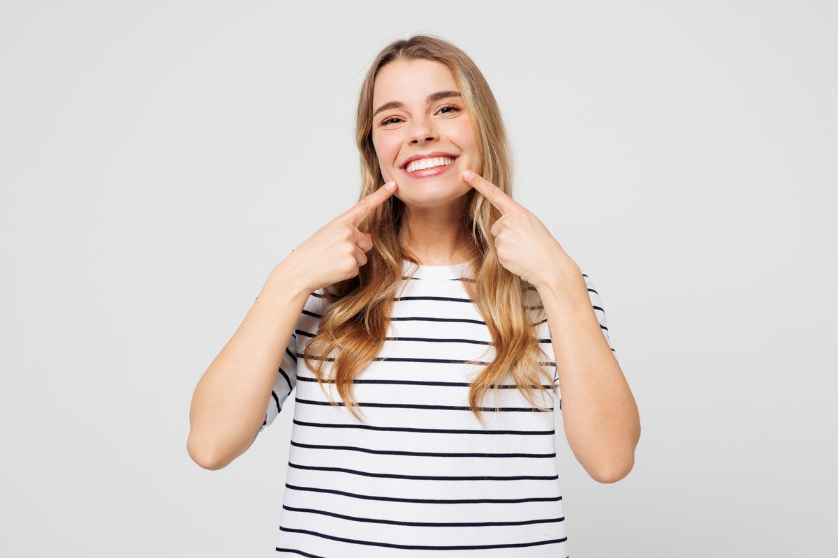cheerful woman wear striped t-shirt casual clothes point index fingers on opened mouth teeth isolated on plain solid white background studio portrait.
